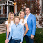 family girl in white shirt, brother in blue shirt mother in white shirt dad in blue blazer posing in front of house in Lincoln park chicago