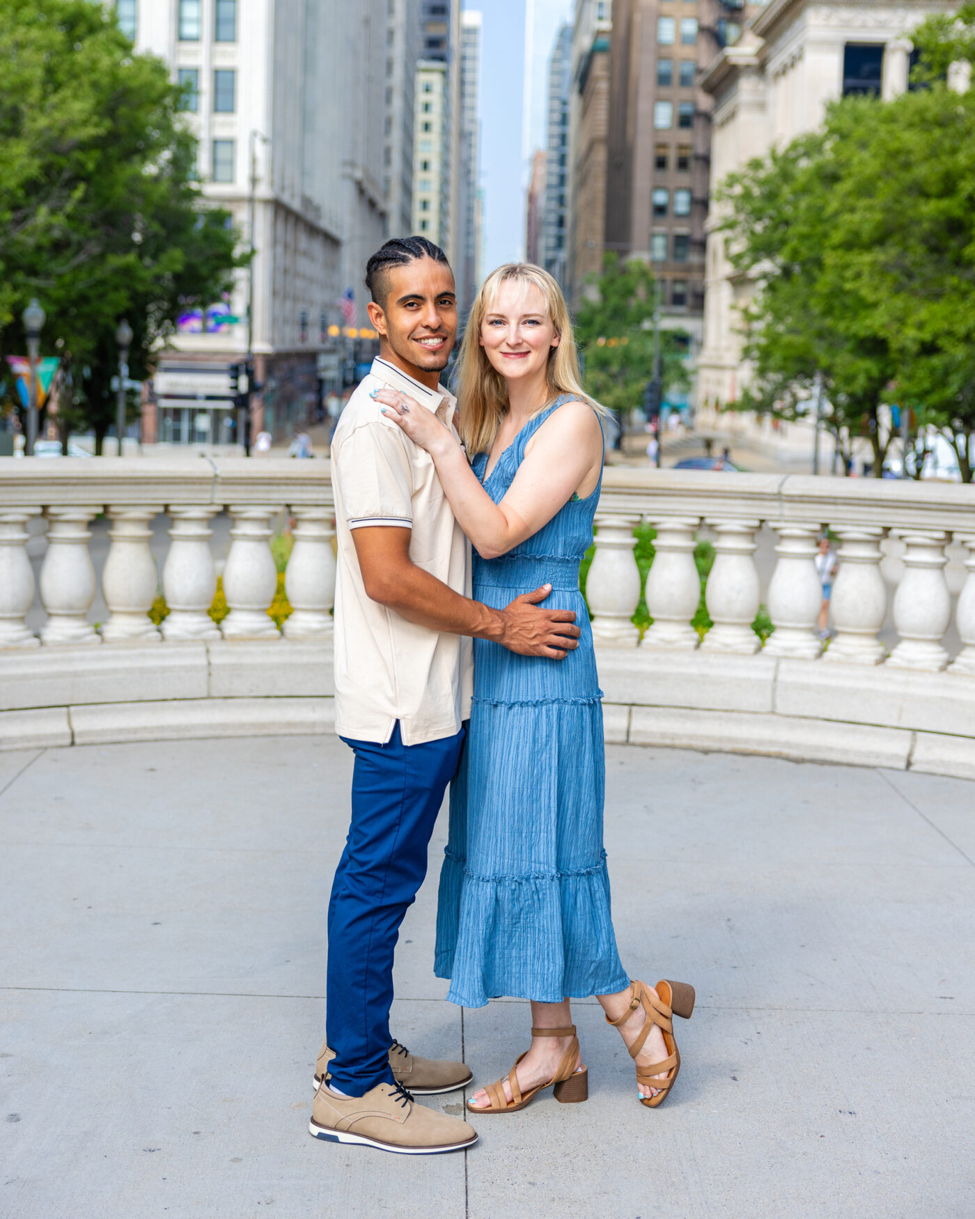 man in white shirt holding woman in blue dress in millennium park at engagement photoshoot